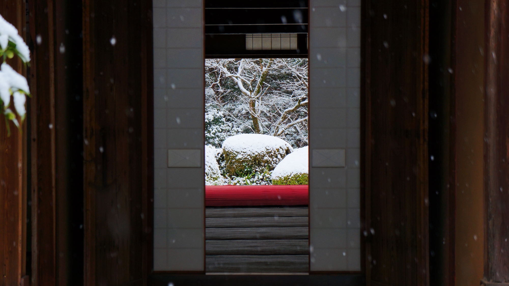 障子の隙間から見える風情ある雪の庭園と赤い絨毯