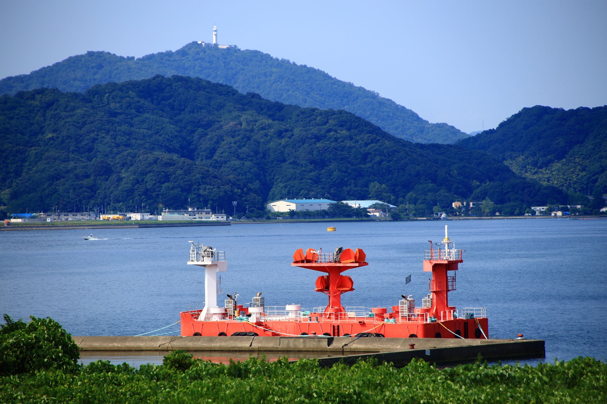 舞鶴湾の赤い船舶のようなものと五老岳と五老スカイタワー