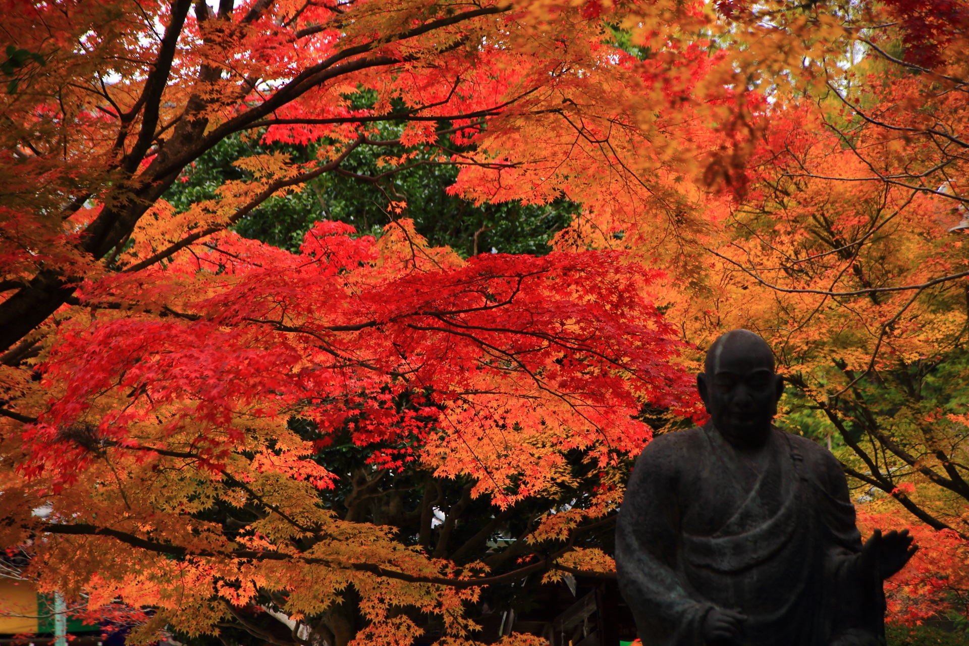 鮮やかな紅葉を背景に佇む子まもり弘法大師
